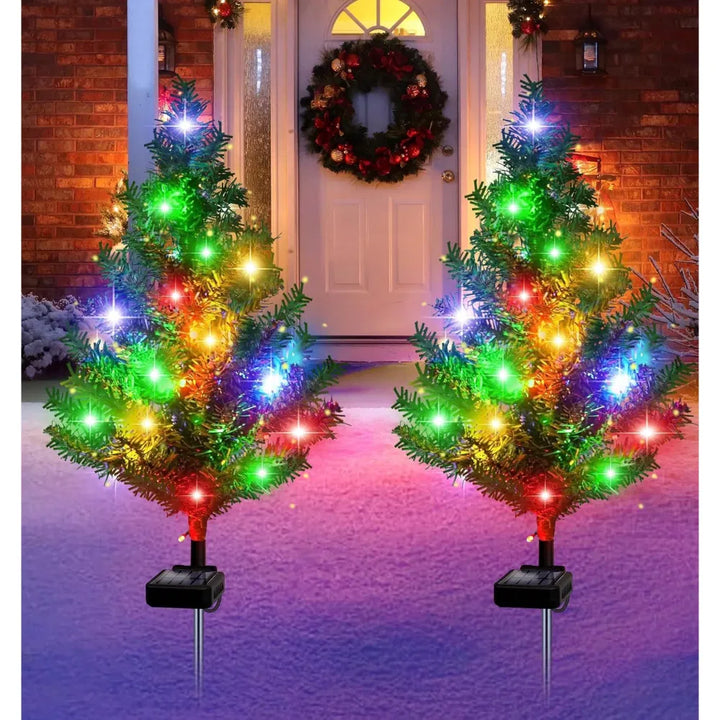 Four solar mini Christmas trees glowing along a path